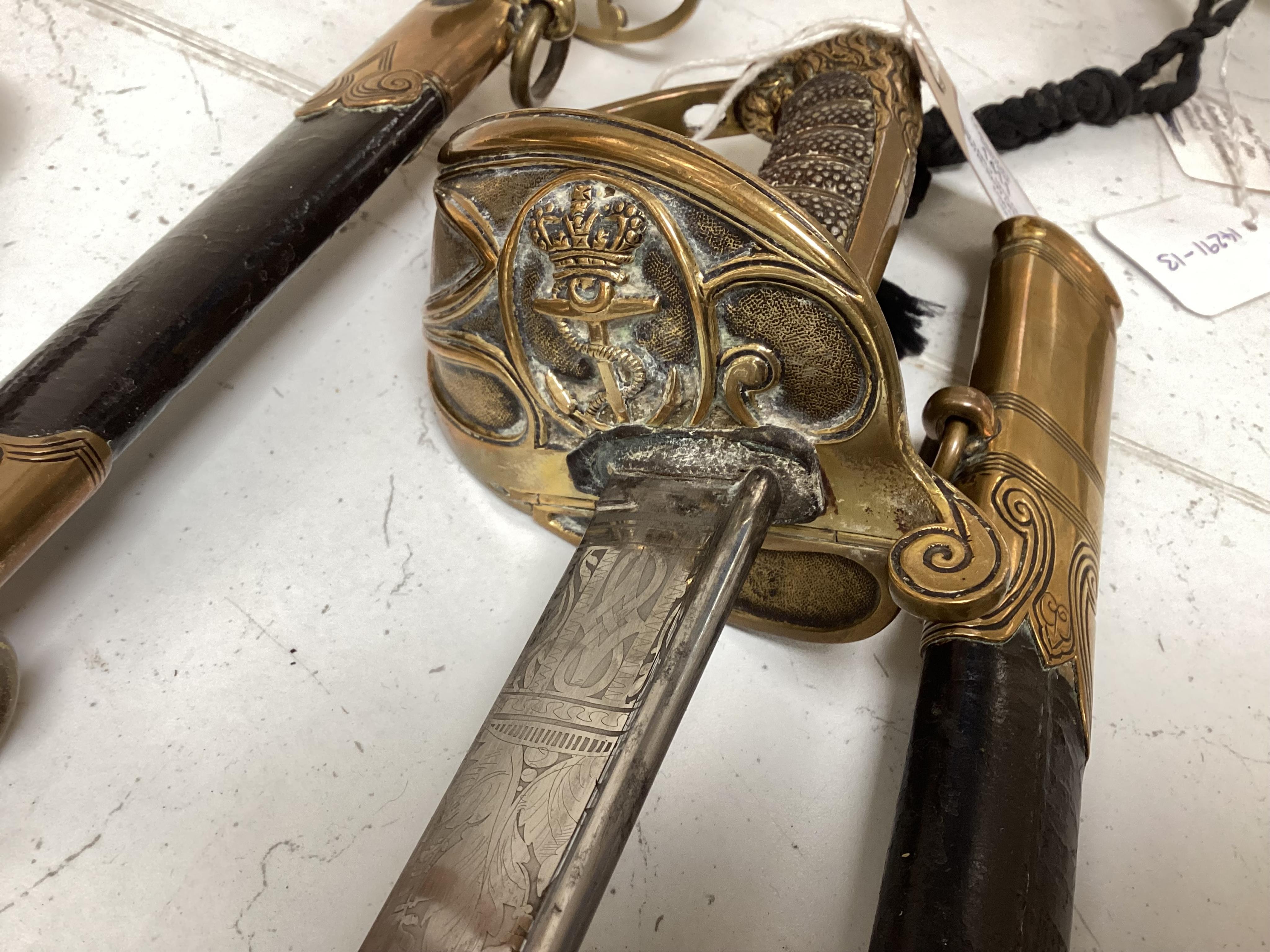 An early 19th century Royal Navy officer's sword with engraved blade, folding knuckle guard, lion’s head pommel and shagreen grip, leather scabbard with brass fittings, blade 73.5cm. Condition - fair, some wear overall.